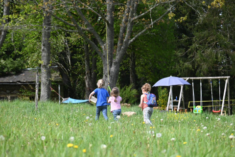 Kinderen spelen op een grasveld bij glampingtenten en schommels bij Glamping Auvergne in de Auvergne-Rhone-Alpes.