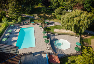 Luchtfoto van zwembaden en ligstoelen bij Huttopia Sarlat - Glamping Dordogne, omgeven door groen en bomen.