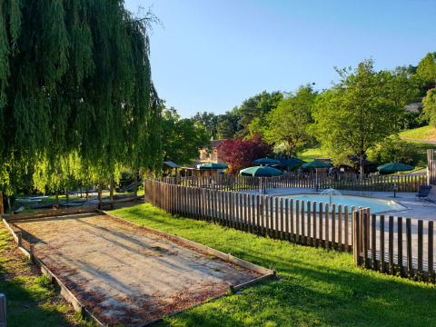 Außenbereich von Huttopia Sarlat - Glamping Dordogne mit Pool, Sonnenschirmen und grüner Natur.