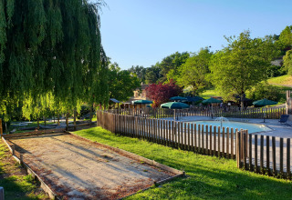 Espace extérieur à Huttopia Sarlat - Glamping Dordogne avec piscine, parasols et verdure luxuriante.