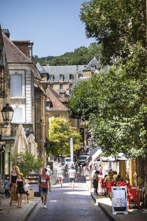 Charmerende gade i Sarlat med cobblestone, caféer og besøgende tæt på Huttopia Sarlat - Glamping Dordogne.