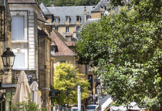 Via pittoresca a Sarlat con caffè e visitatori vicino a Huttopia Sarlat - Glamping Dordogne in Dordogna.