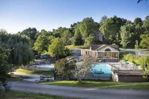 Außenpool und Freizeitbereich bei Huttopia Sarlat - Glamping Dordogne, umgeben von Bäumen und Natur.