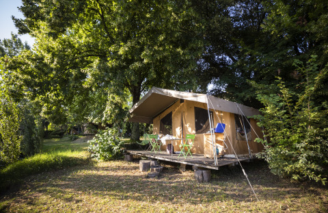 Glamping accommodation at Huttopia Sarlat - Glamping Dordogne, luxury tent on wooden platform amid trees.