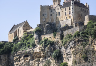 Vista de un castillo medieval en un acantilado cerca de Huttopia Sarlat - Glamping Dordogne en Francia.