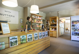 Receptie van Huttopia Sarlat - Glamping Dordogne, met medewerker, brochures en lokale producten zichtbaar.