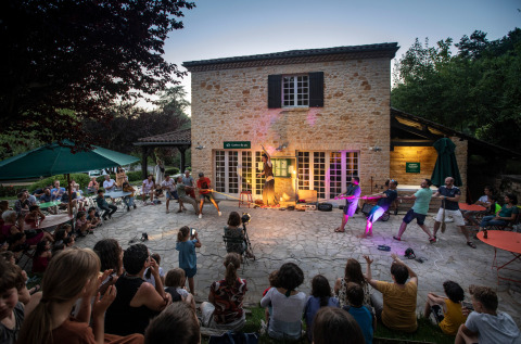 Spectacle en plein air devant des spectateurs chez Huttopia Sarlat - Glamping Dordogne au crépuscule.