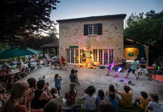 Udendørs underholdning foran gæster ved Huttopia Sarlat - Glamping Dordogne, Frankrig, ved skumring.