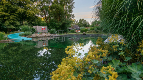 Area glamping naturale con laghetto balneabile, scivolo e vegetazione all’Uhlenköper-Camp Uelzen.