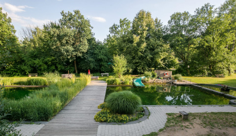 Glampingplek Uhlenköper-Camp Uelzen - Yurts Nedersaksen met houten wandelpad, vijver en veel groen.