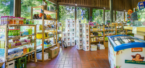 Binnenaanzicht van een ecowinkel op Uhlenköper-Camp Uelzen, met rekken vol natuurproducten en grote ramen.