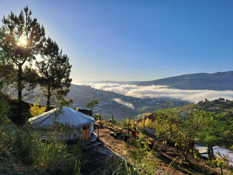 Glamping accommodatie bij Quinta das Corujeiras tussen heuvels, bomen en ochtendmist in de vallei.