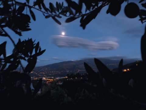 Vista notturna su valli illuminate, luna e nuvole dal glamping Quinta das Corujeiras in Portogallo.