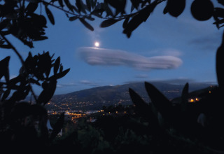 Blick auf beleuchtete Täler bei Nacht mit Vollmond und Wolken vom Glamping Quinta das Corujeiras aus.