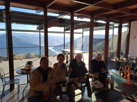 Quatre personnes dégustent du vin avec vue sur les montagnes au glamping Quinta das Corujeiras.