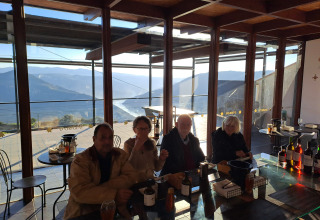 Quattro persone degustano vini con vista sulle montagne al glamping Quinta das Corujeiras.