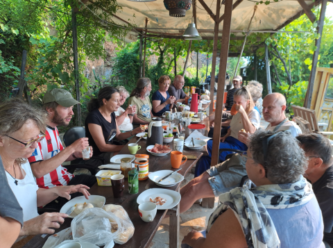 People share a meal outdoors under a canopy at Quinta das Corujeiras glamping accommodation or campsite.