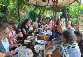Gruppo di persone a pranzo sotto un gazebo al campeggio glamping Quinta das Corujeiras.