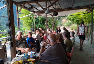 Group of people sharing a meal at an outdoor glamping area at Quinta das Corujeiras surrounded by nature.