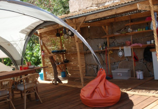 Cucina glamping all'aperto e area lounge con mobili in legno e pouf arancione a Quinta das Corujeiras.