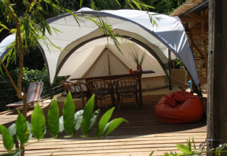 Glamping accommodatie bij Quinta das Corujeiras met tent, houten terras en meubels in een groene omgeving.