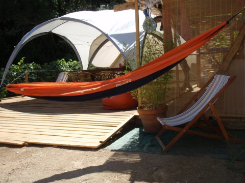 Buitenruimte met oranje hangmat en ligstoel bij glampingaccommodatie Quinta das Corujeiras.