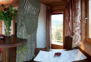 Intérieur d’un hébergement glamping à Baumhaus Hotel Prechtlhof en Autriche, avec un arbre à l’intérieur.