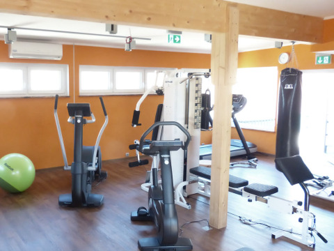 Gimnasio luminoso del Baumhaus Hotel Prechtlhof con equipos de ejercicio, saco de boxeo y acabados en madera.
