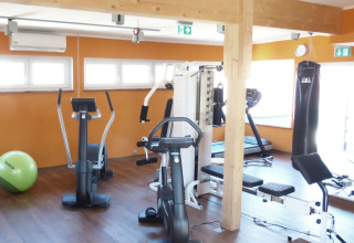 Lyst træningsrum i Baumhaus Hotel Prechtlhof med fitnessudstyr som motionscykler og boksebold.