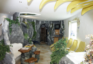 Interno glamping unico al Baumhaus Hotel Prechtlhof con rocce artificiali, piante verdi e sdraio a strisce.