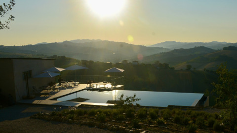 Infinity-Pool und Liegestühle bei Sonnenuntergang im Brezza di sera agriturismo Glamping in Le Marche.