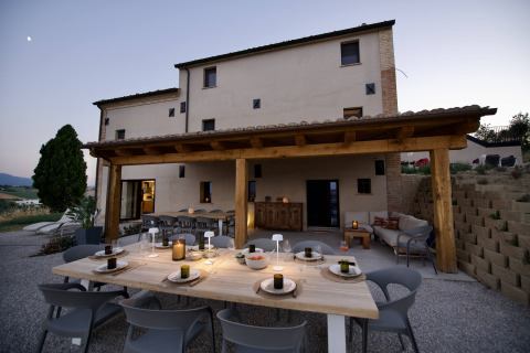 Außenterrasse mit gedecktem Tisch bei Brezza di sera agriturismo - Glampingtenten Le Marche in Italien.