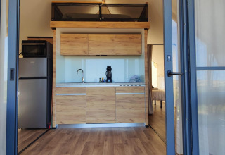 Cocina moderna en tienda glamping de Brezza di sera agriturismo, Le Marche, con dormitorio visible al fondo.