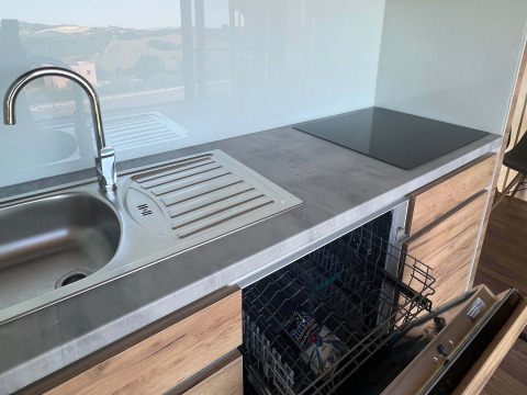 Moderne køkkenfaciliteter med vask, opvaskemaskine og kogeplade på Brezza di Sera Glamping i Le Marche.