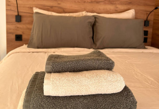 Toallas apiladas sobre una cómoda cama en Brezza di sera agriturismo - Glampingtenten Le Marche, glamping.