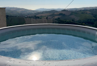 Opvarmet pool med udsigt over det bakkede landskab ved Brezza di sera agriturismo Glampingtenten Le Marche.