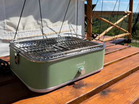 Groene draagbare barbecue op houten terras bij Brezza di sera agriturismo - Glampingtenten Le Marche, glamping.