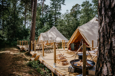 Glampingaccommodatie bij Nordic Woods - Wildernis Glamping Zweden met tenten en houten terras in het bos.