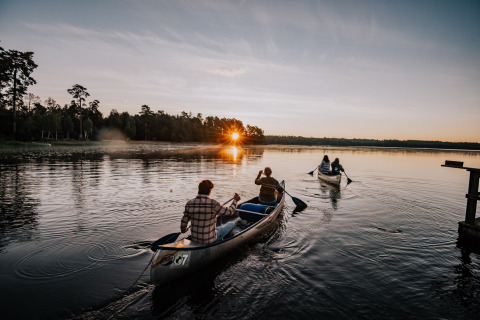 Twee kano’s varen op een meer bij zonsondergang bij Nordic Woods - Wildernis Glamping Zweden in Zweden.