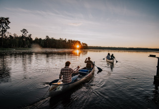 Twee kano’s varen op een meer bij zonsondergang bij Nordic Woods - Wildernis Glamping Zweden in Zweden.