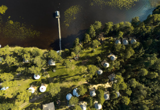 Luchtfoto van Nordic Woods Wildernis Glamping Zweden met tenten aan een meer en omringd door bos.
