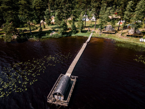 Luchtfoto van Nordic Woods - Wildernis Glamping Zweden met tenten in het bos en sauna op het meer.