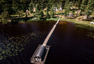 Luchtfoto van Nordic Woods - Wildernis Glamping Zweden met tenten in het bos en sauna op het meer.