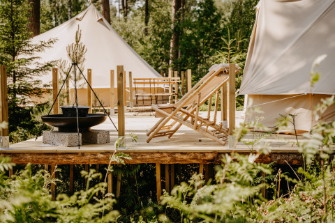 Luxe glamping bij Nordic Woods - Wildernis Glamping Zweden met tenten, houten terras en comfortabele ligstoelen.