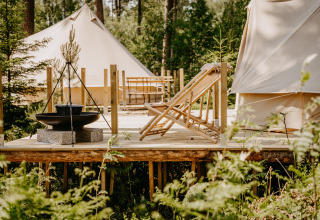Luxe glamping bij Nordic Woods - Wildernis Glamping Zweden met tenten, houten terras en comfortabele ligstoelen.