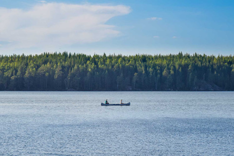 Twee mensen kanoën op een rustig meer met bos op de achtergrond bij Nordic Woods - Wildernis Glamping Zweden.