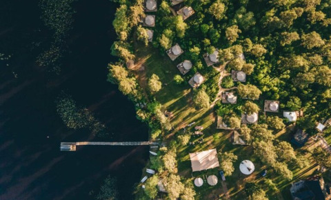 Luchtfoto van Nordic Woods - Wildernis Glamping Zweden met glamping tenten aan een bosrijk meer in Zweden.