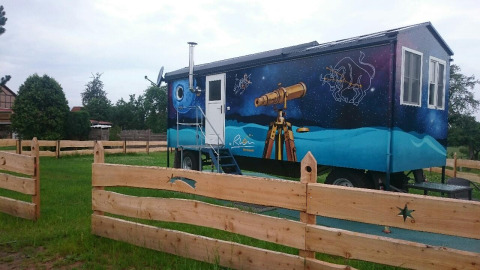 Glamping indkvartering i Thüringen, Zigeunerwagen med stjernehimmelmaleri og teleskop uden for hegnet.