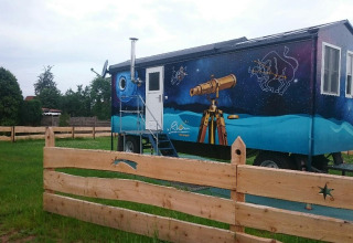 Alloggio glamping in Turingia, carro decorato con costellazioni e telescopio, recintato in legno.