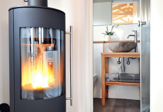 Interior de glamping con estufa y baño moderno en Zur Grünen Kutte - Zigeunerwagen Thüringen camping.